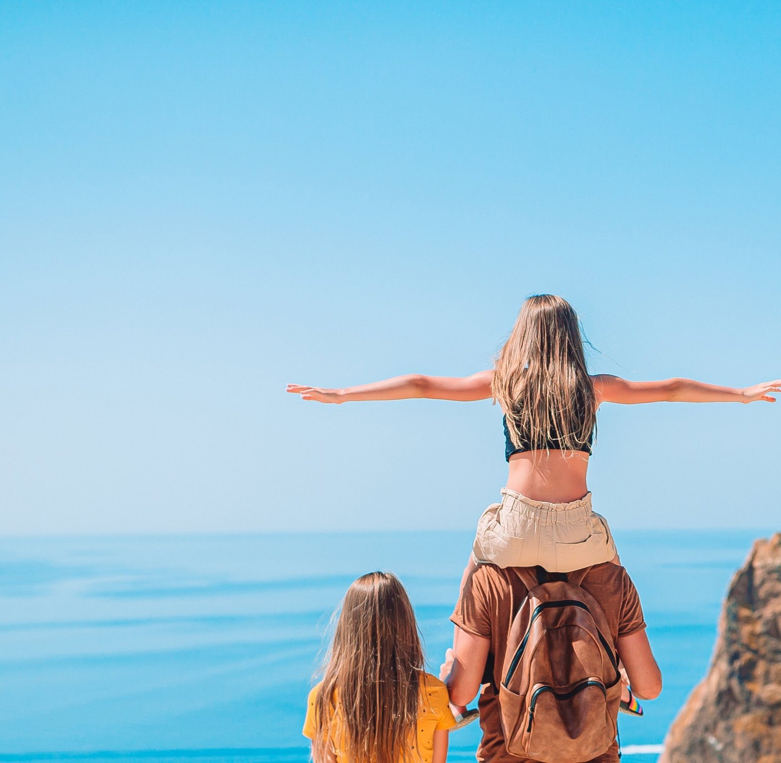 A family looking out over the ocean from a coastal overlook